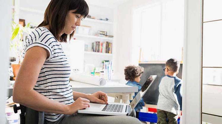 Woman at laptop with children in the background.